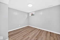 White ceiling with a flush-mount circular light fixture, light gray walls, wood-finish flooring, and a single window - 