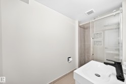Floating vanity with integrated sink, matte black single-handle faucet, glass-enclosed shower with subway tile surround, and decorative accent tile - 