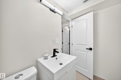 White vanity with an integrated sink and matte black faucet, wall-mounted light fixture, and white paneled door with black hardware - 