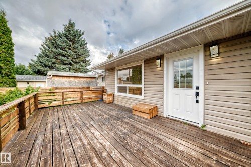 Expansive wood deck with a wood railing, beige horizontal siding, white exterior door with glass panels, and a large exterior window - 7603 130 Avenue Nw, Edmonton, AB - Outdoor With Deck Patio Veranda With Exterior