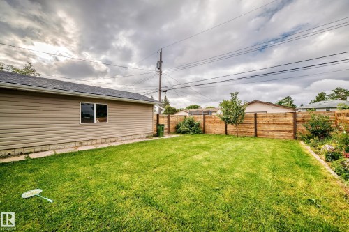 Expansive grassy yard area with a horizontal wood fence and decorative plantings - 7603 130 Avenue Nw, Edmonton, AB - Outdoor