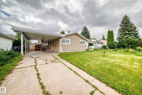 Carport with concrete driveway, light-toned siding exterior, and well-maintained front lawn - 7603 130 Avenue Nw, Edmonton, AB - Outdoor