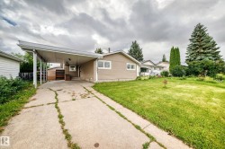 Carport with concrete driveway, light-toned siding exterior, and well-maintained front lawn - 