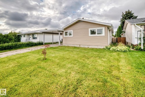 Tan siding exterior with white trim windows and a covered carport - 7603 130 Avenue Nw, Edmonton, AB - Outdoor