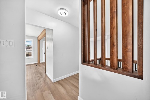 Wood-finish flooring throughout, white baseboards, and a contemporary wood slat railing - 7603 130 Avenue Nw, Edmonton, AB - Indoor Photo Showing Other Room
