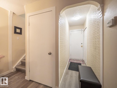 Archway entry with decorative wallpaper, ceiling-mounted light fixture, and wood-finish flooring - #No 510 Abbottsfield Rd Nw Nw, Edmonton, AB - Indoor Photo Showing Other Room