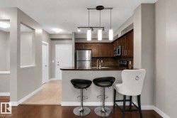 Kitchen featuring dark wood cabinetry, stainless steel appliances, a breakfast bar, and pendant lighting - 