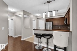Wood-finish flooring throughout, kitchen with dark wood cabinetry, stainless steel appliances, and a mosaic tile backsplash - 
