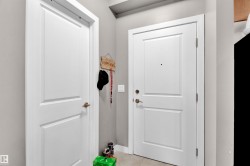 White paneled doors with bronze hardware, light gray wall finish, and tiled flooring - 