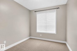 Neutral-toned walls, plush carpeting, and a window with horizontal blinds - 