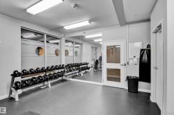Gym space featuring rubber flooring, mirrored wall, and frosted glass windows - 