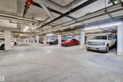 Underground parking garage featuring concrete flooring, exposed overhead piping, and integrated fluorescent lighting - 