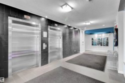 Dual stainless steel elevators set within a black tile wall - 