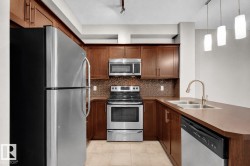 Stainless steel appliance package, rich wood-finish cabinetry, mosaic tile backsplash, double basin sink, and pendant lighting - 