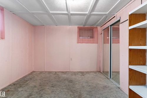 Recessed ceiling with acoustic tiles, built-in shelving, mirrored sliding closet doors, and wall paneling - 5404 45 Avenue, Wetaskiwin, AB - Indoor Photo Showing Other Room
