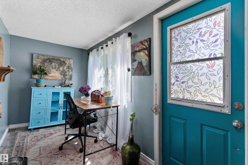 Teal entry door with decorative window film, wood-finish flooring, and light gray wall paint - 5404 45 Avenue, Wetaskiwin, AB - Indoor