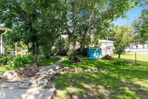 Expansive green space featuring mature trees, a paved pathway, and a stone retaining wall - 5404 45 Avenue, Wetaskiwin, AB - Outdoor