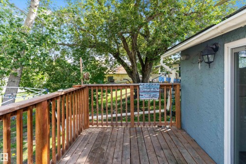 Wood deck with natural finish, featuring a sliding glass door and exterior wall sconce - 5404 45 Avenue, Wetaskiwin, AB - Outdoor With Deck Patio Veranda