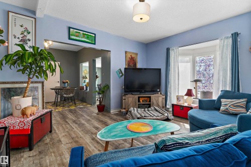 Wood-finish flooring throughout, light blue wall paint, and a bay window - 5404 45 Avenue, Wetaskiwin, AB - Indoor Photo Showing Living Room