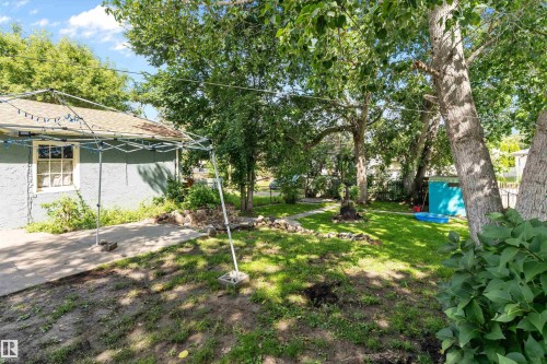 Expansive yard featuring mature trees, a manicured lawn, and a paved pathway - 5404 45 Avenue, Wetaskiwin, AB - Outdoor