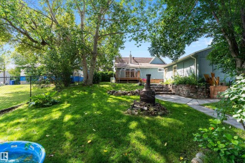 Expansive lawn area, mature trees, tiered stone steps, paved walkway, and a raised planting bed with stone retaining wall - 5404 45 Avenue, Wetaskiwin, AB - Outdoor With Deck Patio Veranda