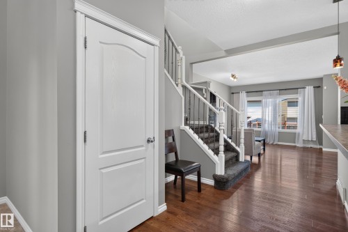 Hardwood-finish flooring, staircase with carpeted treads and wrought iron spindles, and large window with white window treatments - 9515 221 Street Nw, Edmonton, AB - Indoor Photo Showing Other Room