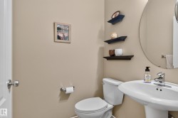 Pedestal sink with chrome faucet, circular wall mirror, and built-in wall shelving - 