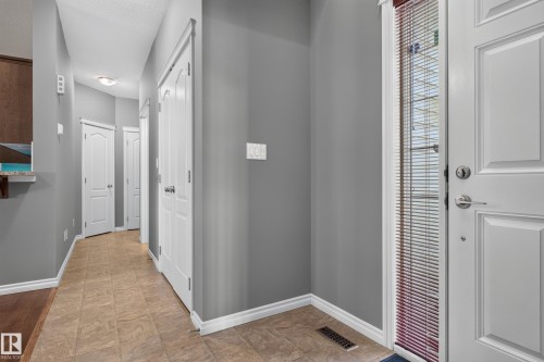 Entryway with tile flooring, gray wall finishes, a white paneled door, and a full-length sidelight with blinds - 9515 221 Street Nw, Edmonton, AB - Indoor Photo Showing Other Room