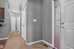 Entryway with tile flooring, gray wall finishes, a white paneled door, and a full-length sidelight with blinds - 