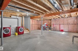 Unfinished basement featuring exposed wood joists, concrete flooring, and insulated perimeter walls - 