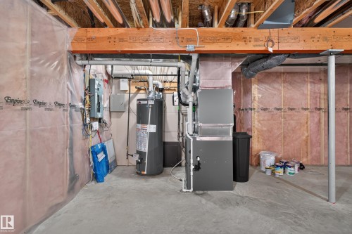Unfinished basement featuring exposed wood joists, concrete flooring, a water heater, and a furnace system - 9515 221 Street Nw, Edmonton, AB - Indoor Photo Showing Basement