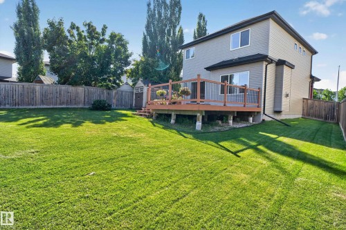 Expansive green lawn, wood privacy fence, multi-level wood deck with dark railings, exterior siding, and a storage shed - 9515 221 Street Nw, Edmonton, AB - Outdoor With Deck Patio Veranda With Backyard