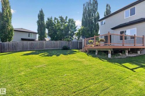 Expansive green lawn, elevated wood deck with railing, sliding glass door access, and a wood privacy fence - 9515 221 Street Nw, Edmonton, AB - Outdoor With Deck Patio Veranda