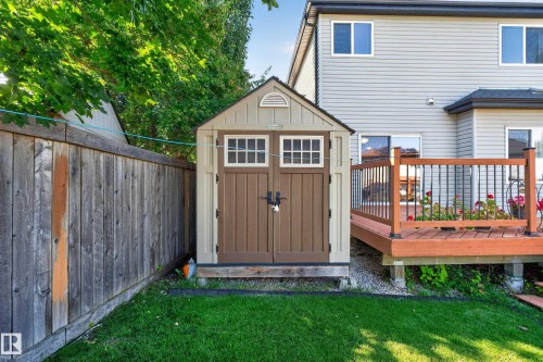 Manicured lawn, wooden fence, exterior shed with double doors, wood deck with black railings, and siding exterior - 9515 221 Street Nw, Edmonton, AB - Outdoor With Deck Patio Veranda With Exterior
