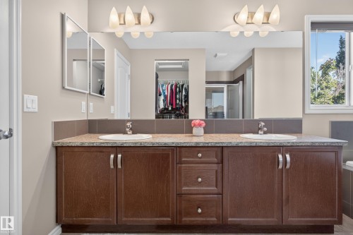 Double vanity with undermount sinks, stone-finish countertop, dark wood-finish cabinetry, and brushed nickel hardware - 9515 221 Street Nw, Edmonton, AB - Indoor Photo Showing Bathroom