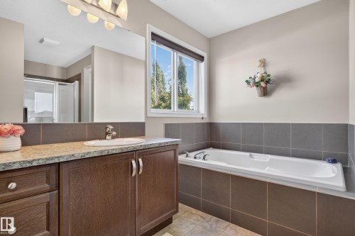 Vanity with a granite-style countertop, undermount sink, and wood-finish cabinetry - 9515 221 Street Nw, Edmonton, AB - Indoor Photo Showing Bathroom