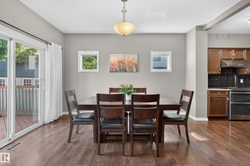 Dining area featuring wood-finish flooring, two large windows, and a sliding glass door providing exterior access - 9515 221 Street Nw, Edmonton, AB - Indoor Photo Showing Dining Room