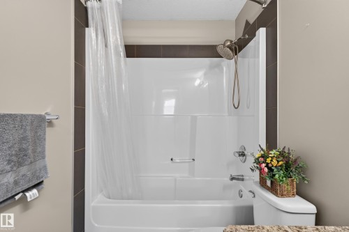 Bathtub and shower combination with a bronzed shower head, chrome fixtures, and dark tile surround - 9515 221 Street Nw, Edmonton, AB - Indoor Photo Showing Bathroom