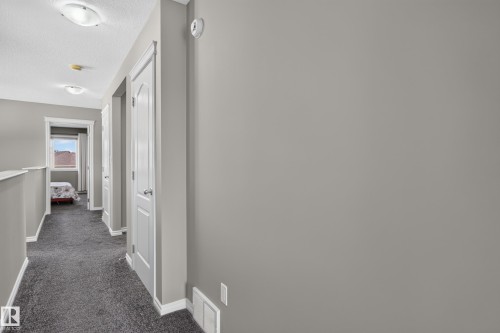 Hallway with gray carpeting, white trim, and white paneled doors - 9515 221 Street Nw, Edmonton, AB - Indoor Photo Showing Other Room