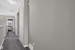Hallway with gray carpeting, white trim, and white paneled doors - 