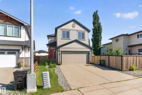 Two-story residence featuring light-colored siding with dark trim accents, an attached garage, and a concrete driveway - 9515 221 Street Nw, Edmonton, AB - Outdoor