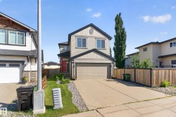 Two-story residence featuring light-colored siding with dark trim accents, an attached garage, and a concrete driveway - 
