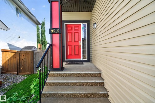 Front entry with concrete steps, black metal railing, and a vibrant red door - 9515 221 Street Nw, Edmonton, AB - Outdoor With Exterior