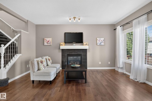 Hardwood flooring, fireplace with tile surround and mantel, white-trimmed windows, and a staircase with white spindles - 9515 221 Street Nw, Edmonton, AB - Indoor Photo Showing Living Room With Fireplace