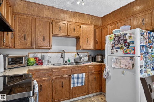 Full-height wood-finish cabinetry, tile backsplash, built-in sink, and kitchen appliances - 18247 93 Avenue Nw, Edmonton, AB - Indoor Photo Showing Kitchen With Double Sink