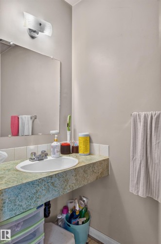 Wall-mounted light fixture, rectangular mirror, integrated sink, and patterned countertop - 18247 93 Avenue Nw, Edmonton, AB - Indoor Photo Showing Bathroom
