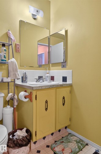 Pedestal sink with chrome faucet, a tri-fold medicine cabinet, and built-in vanity with yellow cabinetry - 18247 93 Avenue Nw, Edmonton, AB - Indoor Photo Showing Bathroom