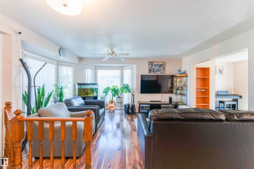 Living area featuring wood-finish flooring, a bay window, and a ceiling fan - 4609 38A Avenue Nw, Edmonton, AB - Indoor Photo Showing Living Room With Fireplace