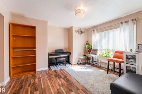 Wood-finish flooring, built-in shelving, chandelier light fixture, and window with vertical blinds - 4609 38A Avenue Nw, Edmonton, AB - Indoor Photo Showing Other Room