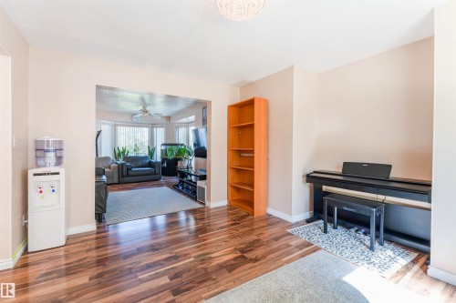 Wood-finish flooring throughout, light-toned wall paint, and an arched entry to an additional living space - 4609 38A Avenue Nw, Edmonton, AB - Indoor Photo Showing Living Room